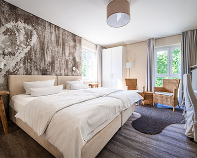 Hotelzimmer im Hotel Anders in creme mit Doppelbett und Sessel-Ecke