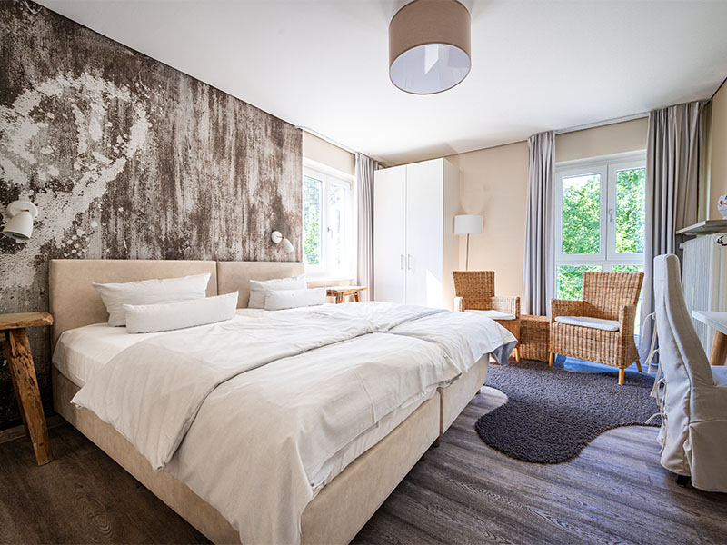 Hotelzimmer im Hotel Anders in creme mit Doppelbett und Sessel-Ecke