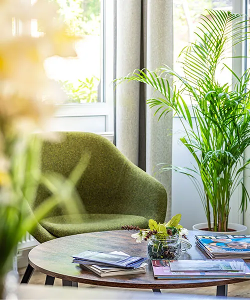 Zwei grüne Sessel und ein Couchtisch mit Zeitungen in einer Hotelecke