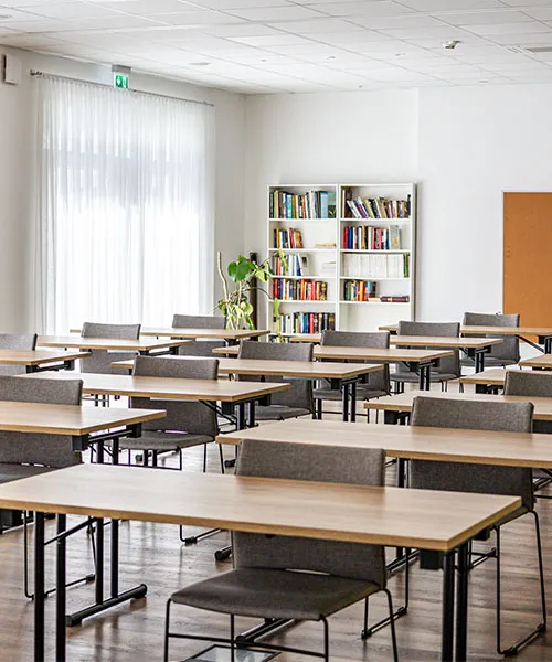 Tagungsraum mit Tischen und grauen Stühlen in Raumaufteilung
