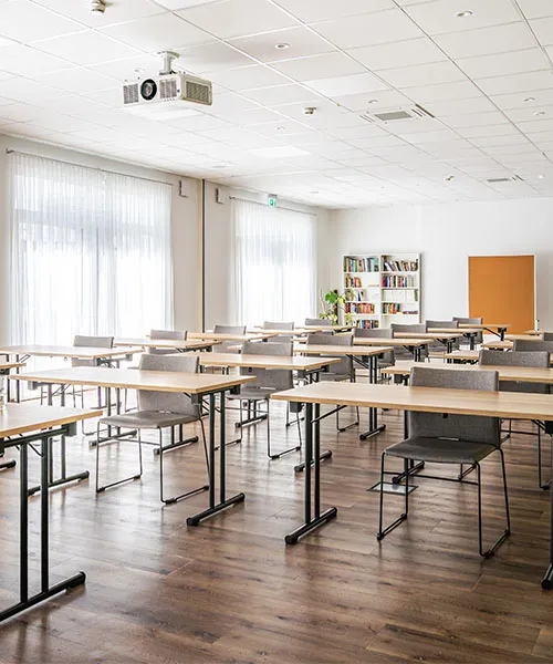 Tagungsraum mit Tischen und grauen Stühlen in Raumaufteilung