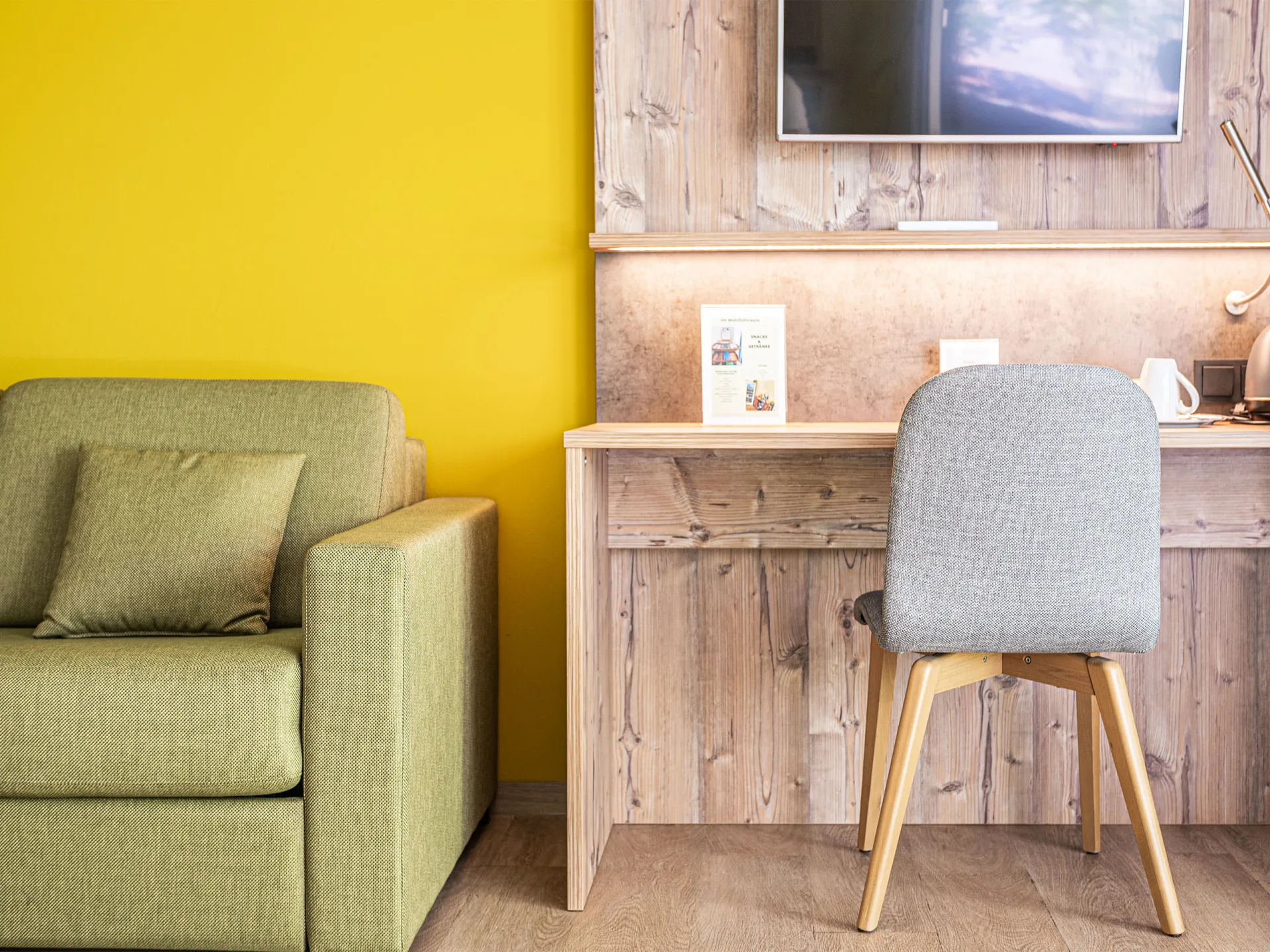 Hotelzimmer mit grüner Couch und Tisch mit Stuhl