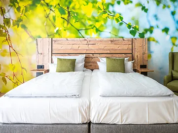 Doppelbett vor grüner Wand im Hotelzimmer