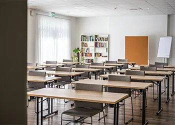 Tagungsraum mit Tischen und grauen Stühlen in Raumaufteilung