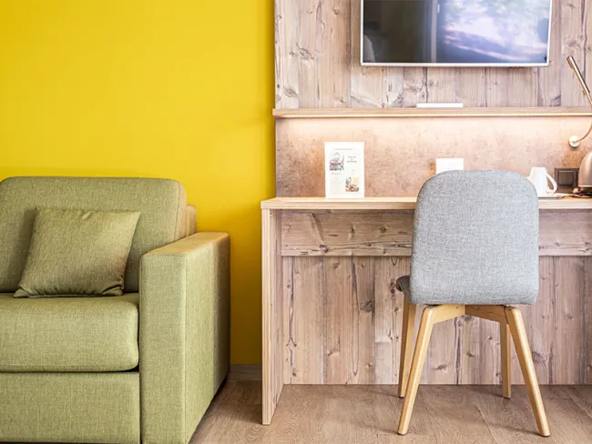 Hotelzimmer mit grüner couch und Tisch mit Stuhl