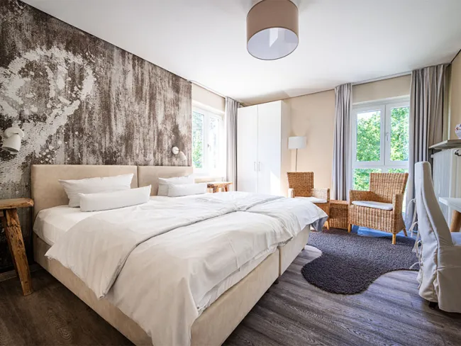 Hotelzimmer im Hotel Anders in creme mit Doppelbett und Sessel-Ecke